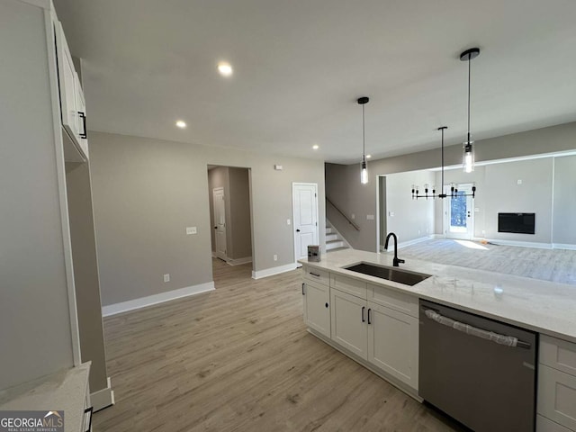 kitchen with light wood-type flooring, sink, light stone counters, white cabinets, and stainless steel dishwasher