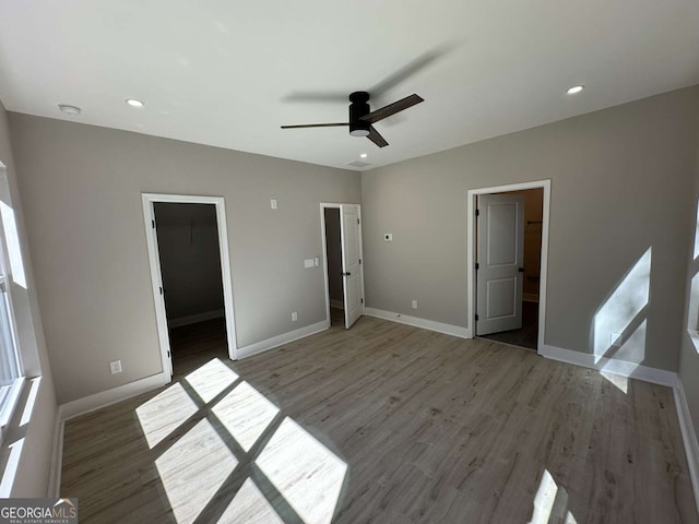 unfurnished bedroom featuring dark hardwood / wood-style floors, a walk in closet, ensuite bathroom, and ceiling fan