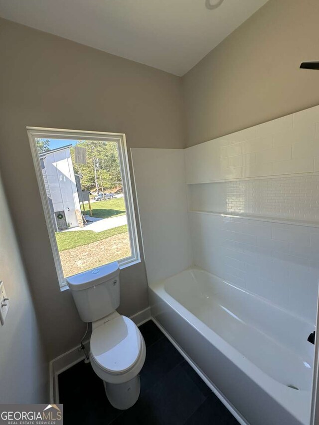 bathroom featuring tile patterned floors, a tub, and toilet