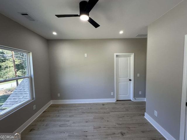 empty room with ceiling fan and light hardwood / wood-style flooring