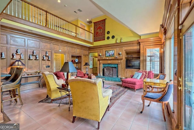 living room with wooden walls, light tile patterned flooring, and a high ceiling