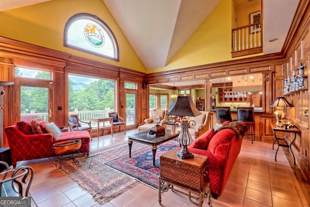 tiled living room featuring ornate columns, high vaulted ceiling, and indoor bar