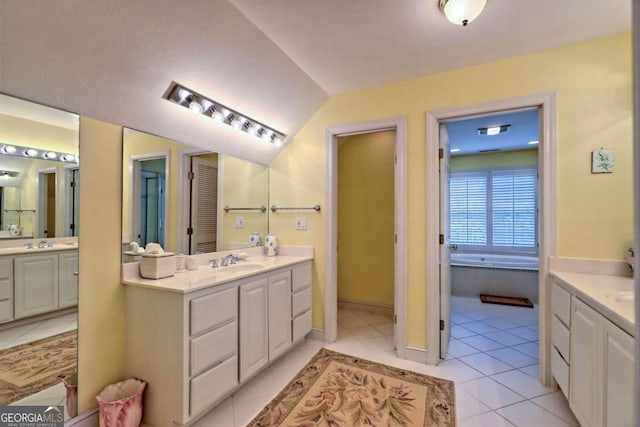 bathroom with tile patterned floors, vanity, a relaxing tiled tub, and vaulted ceiling