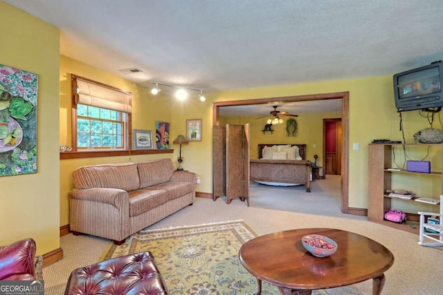 carpeted living room with ceiling fan and a textured ceiling