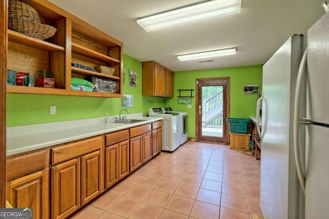 kitchen with washer and clothes dryer, sink, light tile patterned floors, and white refrigerator