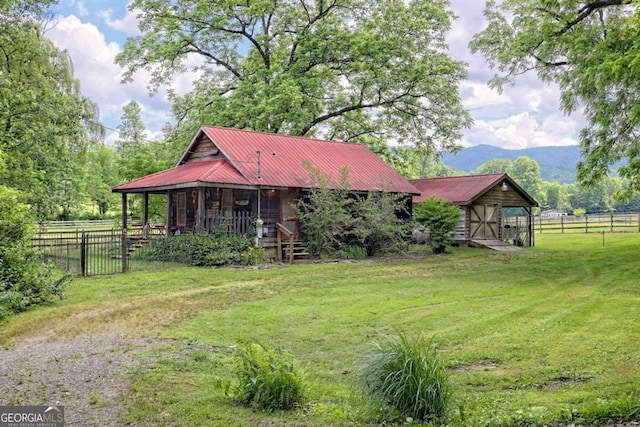 view of front of house featuring a mountain view, an outdoor structure, and a front lawn