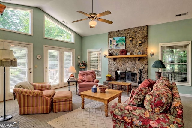 carpeted living room with high vaulted ceiling, a stone fireplace, ceiling fan, and a healthy amount of sunlight