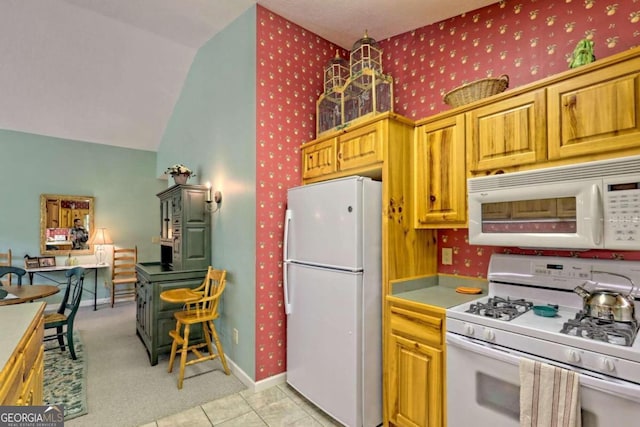 kitchen with vaulted ceiling, light tile patterned floors, and white appliances