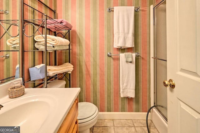 bathroom featuring tile patterned flooring, vanity, a shower with shower door, and toilet