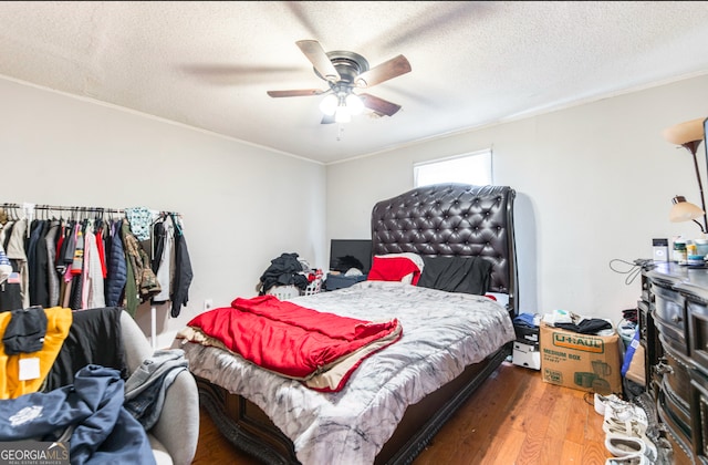 bedroom with hardwood / wood-style floors, a textured ceiling, ceiling fan, and crown molding