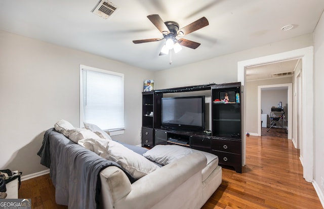 living room featuring ceiling fan and dark wood-type flooring