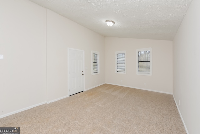 carpeted empty room with a textured ceiling and vaulted ceiling