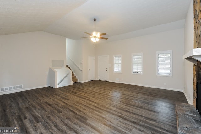 unfurnished living room with ceiling fan, dark hardwood / wood-style floors, a stone fireplace, and vaulted ceiling