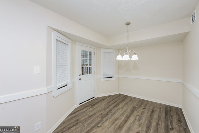 unfurnished dining area featuring a chandelier and dark hardwood / wood-style floors