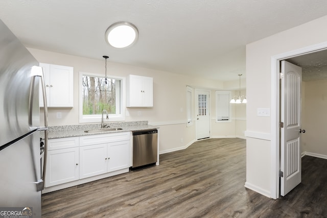 kitchen with pendant lighting, white cabinets, stainless steel appliances, sink, and light stone counters