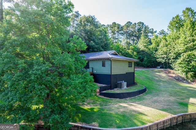 view of side of property featuring central air condition unit and a yard