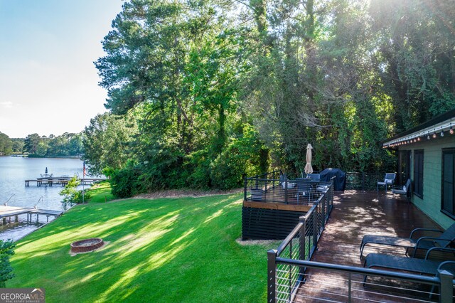 view of yard with a fire pit and a deck with water view