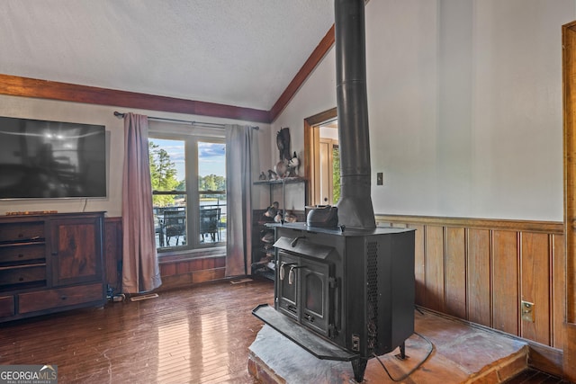 living room featuring a textured ceiling, lofted ceiling, a wood stove, and dark wood-type flooring