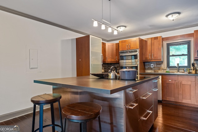 kitchen featuring decorative light fixtures, dark hardwood / wood-style floors, stainless steel double oven, and a breakfast bar area