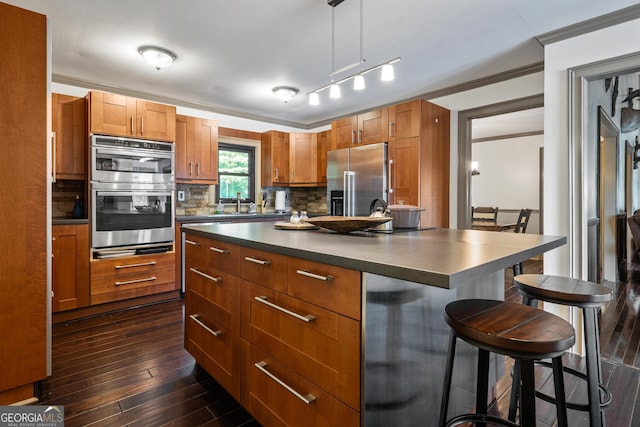 kitchen featuring tasteful backsplash, stainless steel appliances, crown molding, a kitchen island, and hanging light fixtures