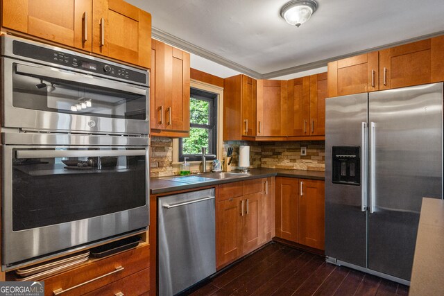 kitchen featuring sink, dark wood-type flooring, tasteful backsplash, appliances with stainless steel finishes, and ornamental molding