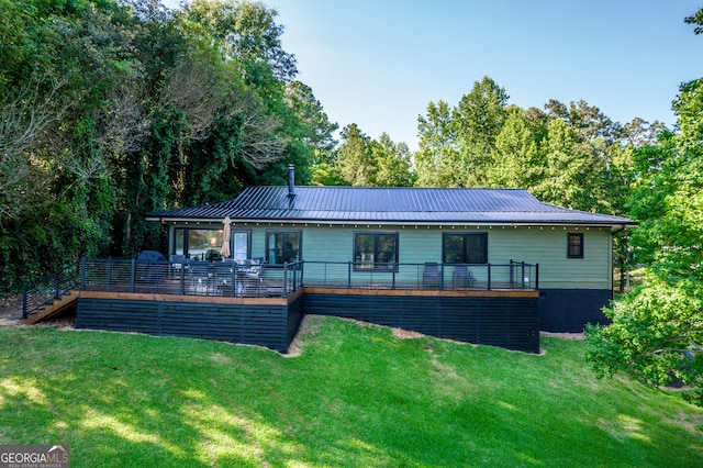 rear view of house featuring a wooden deck and a yard