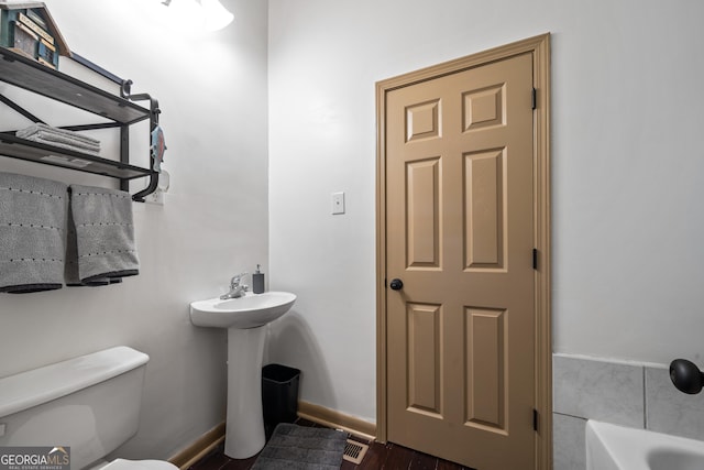 bathroom featuring toilet and a tub to relax in