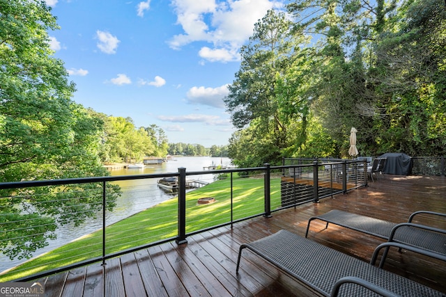 wooden deck with grilling area, a yard, and a water view