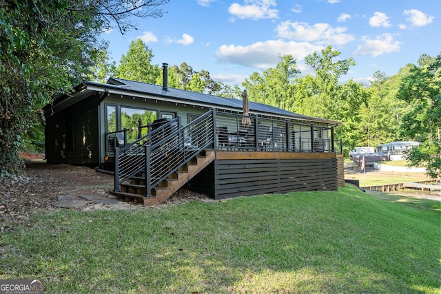 rear view of house with a wooden deck and a yard