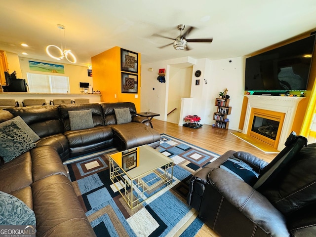 living room with ceiling fan with notable chandelier and hardwood / wood-style floors