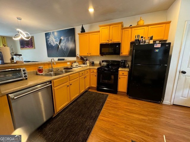 kitchen with black appliances, hanging light fixtures, decorative backsplash, light wood-type flooring, and sink