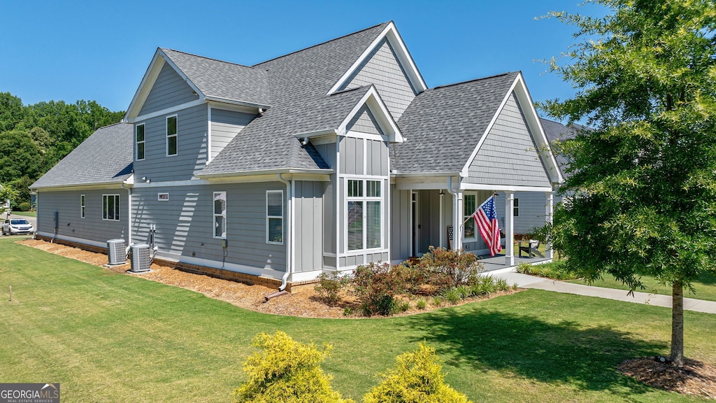 view of front of home with central AC unit, covered porch, and a front yard