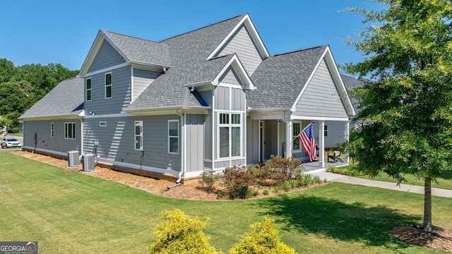 view of front of home with central AC unit, covered porch, and a front yard