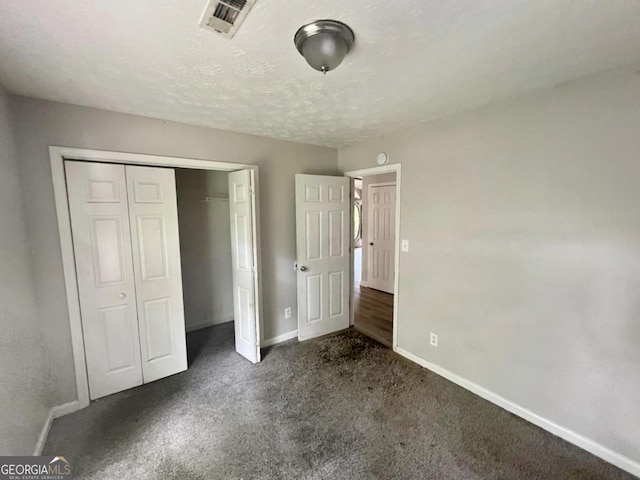 unfurnished bedroom featuring dark carpet, a closet, and a textured ceiling