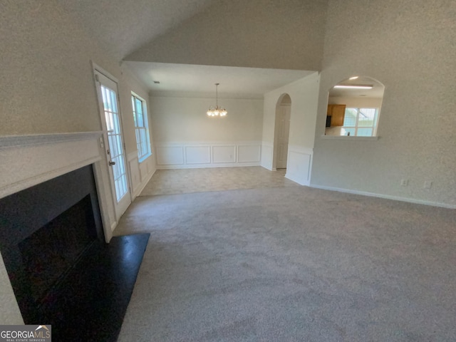 unfurnished living room featuring light colored carpet, an inviting chandelier, and lofted ceiling