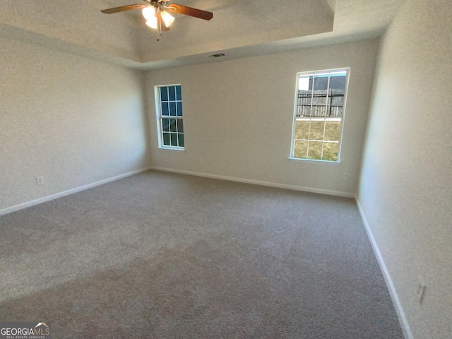 carpeted empty room featuring a tray ceiling and ceiling fan