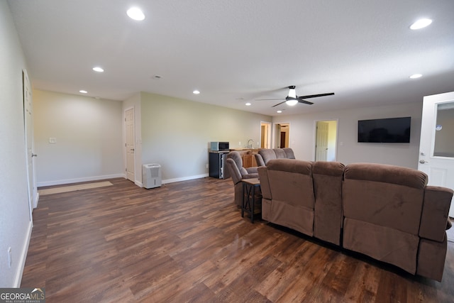 living room featuring ceiling fan and dark wood-type flooring