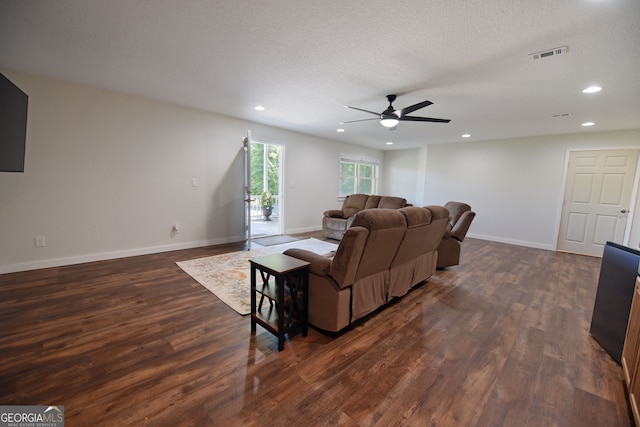 living room with ceiling fan, dark wood-type flooring, and a textured ceiling