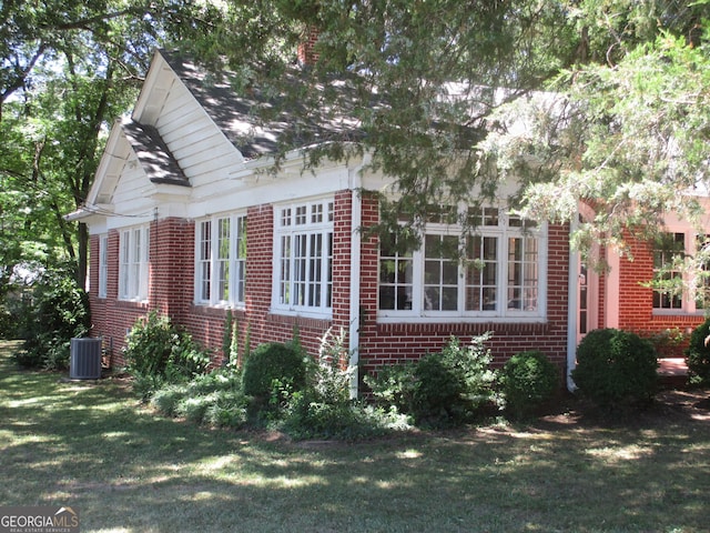 view of side of home with central AC and a yard