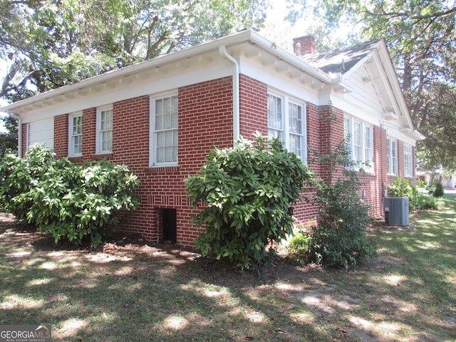 view of side of property with a yard and central AC