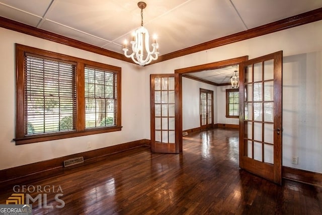 empty room with ornamental molding, french doors, dark wood-type flooring, and a notable chandelier