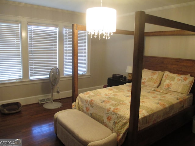 bedroom featuring crown molding, dark hardwood / wood-style floors, and a notable chandelier