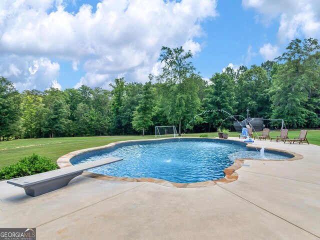 view of swimming pool featuring a patio, a diving board, pool water feature, and a lawn