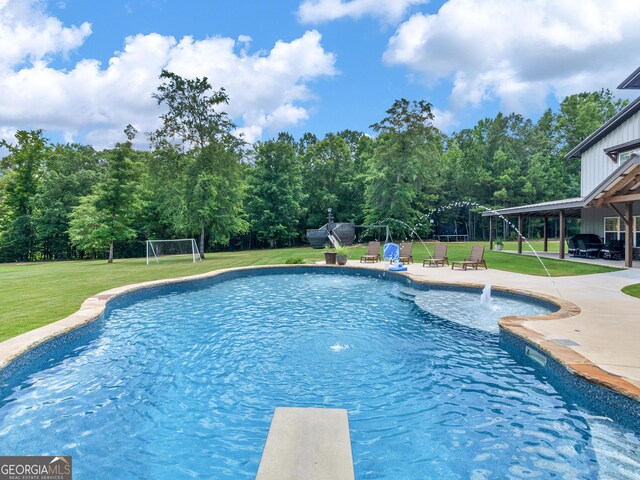 view of pool with a patio, pool water feature, a diving board, and a yard