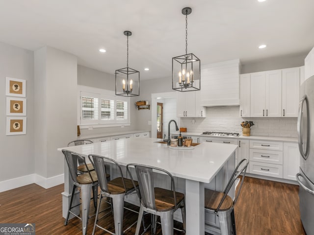 kitchen with decorative light fixtures, an island with sink, dark hardwood / wood-style floors, and stainless steel appliances