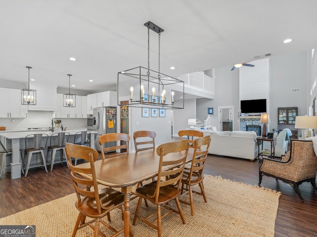 dining space featuring an inviting chandelier, a towering ceiling, and dark wood-type flooring