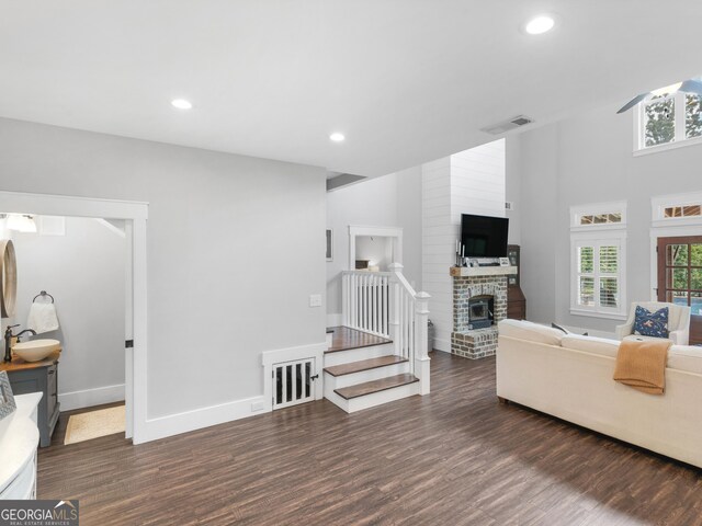 living room featuring brick wall, dark hardwood / wood-style flooring, a brick fireplace, and sink