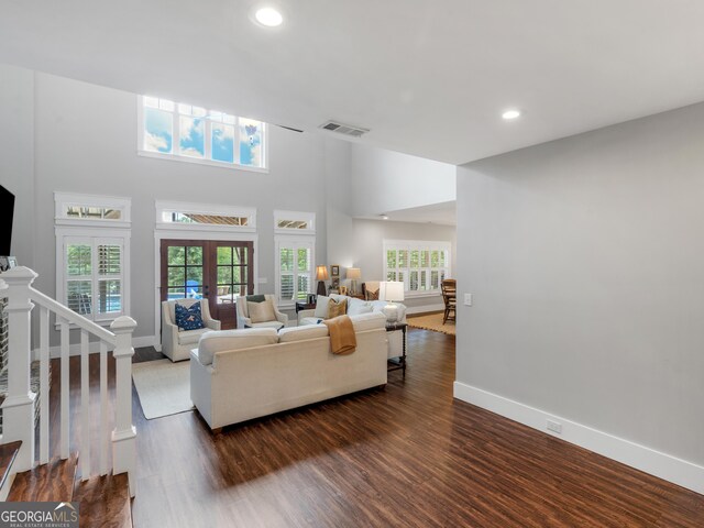 living room with a wealth of natural light, a high ceiling, french doors, and dark wood-type flooring