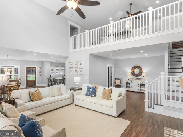 living room with dark hardwood / wood-style floors, ceiling fan with notable chandelier, and a high ceiling