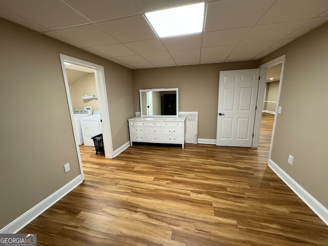 unfurnished bedroom featuring a drop ceiling, washing machine and clothes dryer, and wood-type flooring